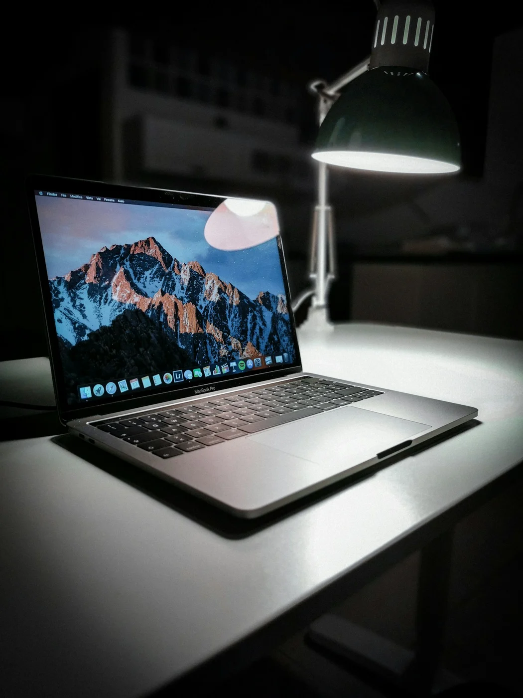 Notebook sobre mesa iluminada por uma luminária