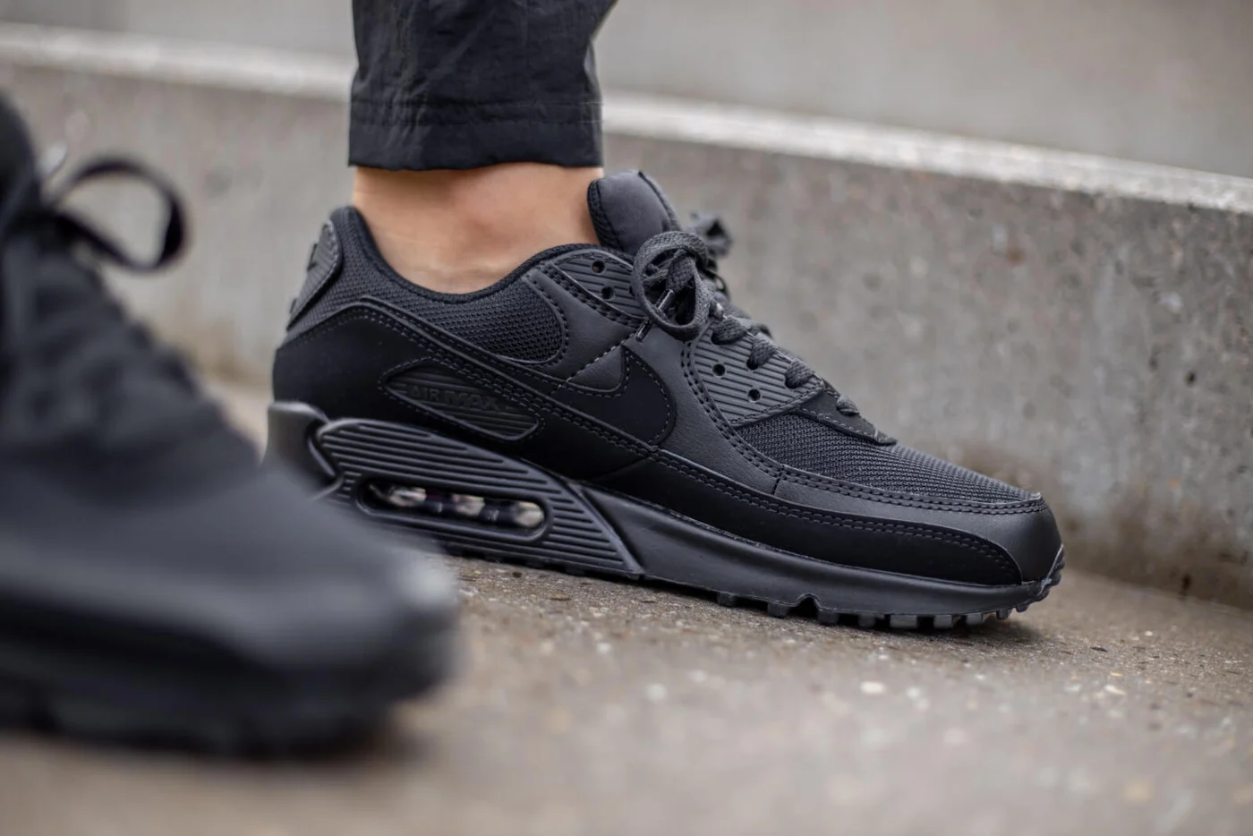 Tênis Nike Air Max preto sobre degraus de concreto